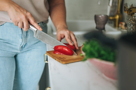 Beautiful smiling brunette young woman plus size body positive using laptop in kitchen at homeの写真素材