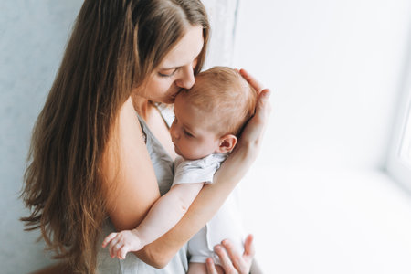 Young mother having fun with cute baby girl on bed, natural tones, selective focusの写真素材