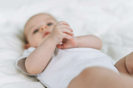 Cute baby girl 2-4 month on bed with white linen, natural tones, selective focusの写真素材