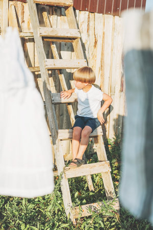 Cute blonde climbs up the ladder countryside cottagecor on summerの写真素材