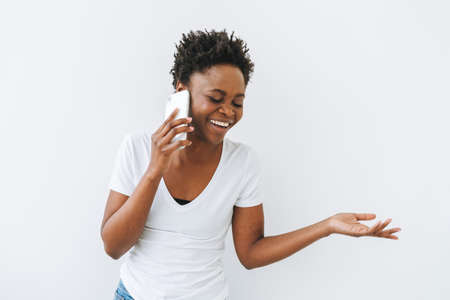 Portrait of charming smiling beautiful young African American woman in white t-shirt isolated on...
