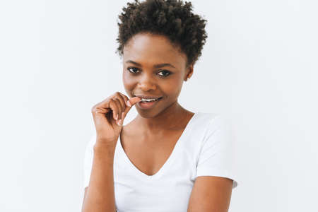 Portrait of charming smiling beautiful young African American woman in white t-shirt isolated on white backgroundの写真素材