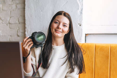 Brunette smiling young woman photographer working with her camera and laptop in the cafeの写真素材