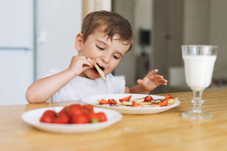 Toddler boy have fun while cooking with flour at the table in kitchen at home. Boy playing with toyの写真素材