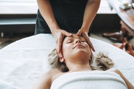 Young blonde woman enjoys facial massage with microcurrent facial massager in the spa, treat yourself. Professional body careの写真素材