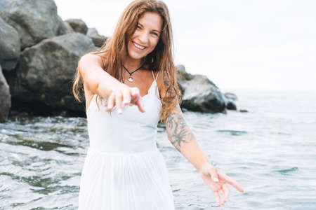 Young fit beautiful woman with long hair in white sport clothes practice yoga and meditation on sea...