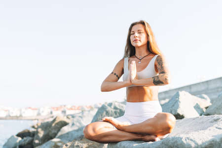 Young fit beautiful woman with long hair in white sport clothes practice yoga and meditation on the...