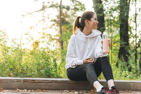 Crop photo of Young slim woman brunette in the sport clothes running at forest on golden hour sunrise time. Health and wellness, fitness lifestyleの写真素材
