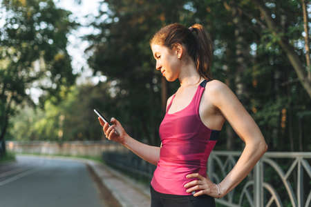 Young slim woman brunette in sport clothes doing stretching at forest on the golden hour sunrise...