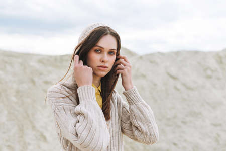 Fashion beauty portrait of young woman with long hair in green organic suit on desert background