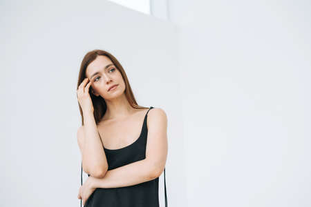 Fashion beauty portrait of young woman with dark long hair on evening elegant black dress with open back on sparkle backgroundの写真素材