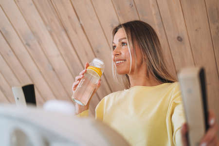 Young beautiful woman forty year with blonde long curly hair in cozy knitted gray sweater with...