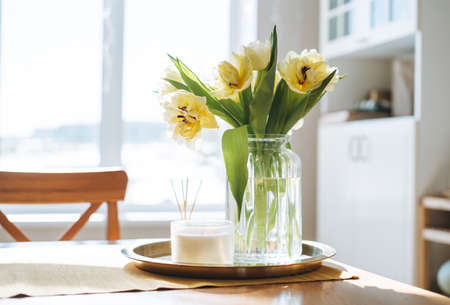Beautiful bouquet of yellow tulips in vase at home, natural background
