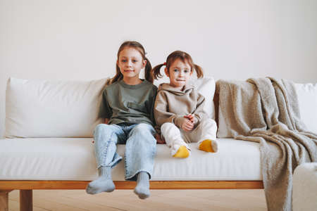 Cute little sisters girls looking in window at the home, people from behindの写真素材