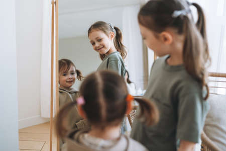 Cute little sisters girls looking in window at the home, people from behindの写真素材