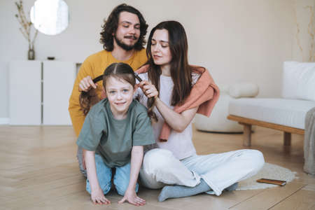Young family with child little girl on the gray wall background, parents using mobile phones