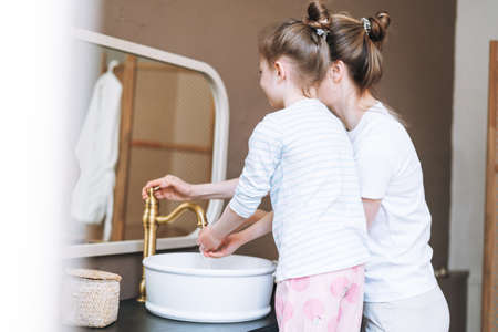 Young mother woman and little tween girl daughter having fun in the bath with foam at homeの写真素材
