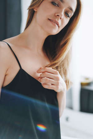 Close up beauty portrait of young woman with long hair on evening elegant black dress in white interiorの写真素材