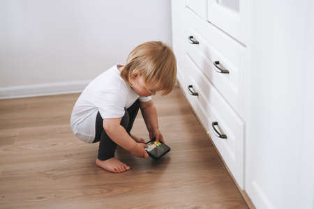 Cute funny baby girl happy child in home clothes sitting on commode at home