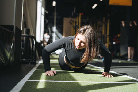 Young brunette woman training for cardio equipment at fitness club gym