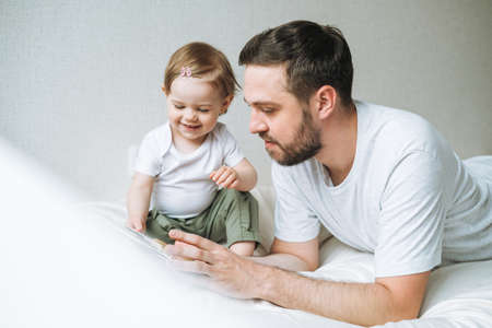 Happy father young man and baby girl little daughter having fun playing with toy in children room at home, selective focusの写真素材