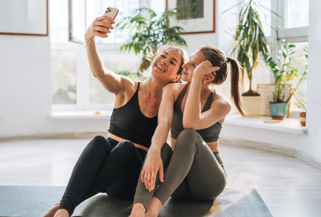 Young fit women practice yoga doing asana in a bright yoga studio. Yoga ticher helps doing asana exercises with student in yoga classの写真素材