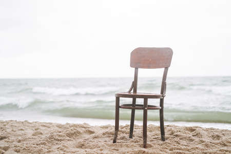 Vintage wooden chair on the sand by the sea in a stormの写真素材