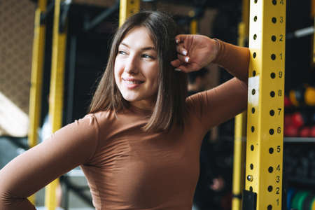 Young brunette woman doing stretching pilates, practice yoga on mat in fitness club gym