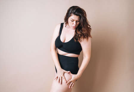 Portrait of self loving woman plus size in underwear on beige background, body loveの写真素材