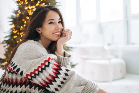 Crop photo of young woman in nordic sweater packing gift box at home, top viewの写真素材
