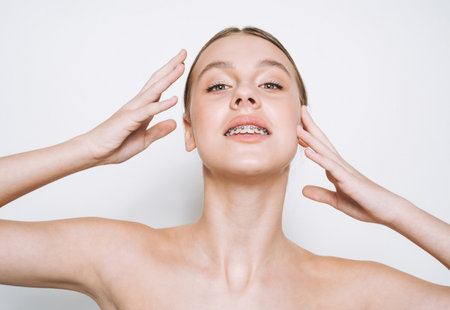 Beauty portrait of funny young girl with fresh skin, teenager with braces on teeth on white background isolatedの写真素材