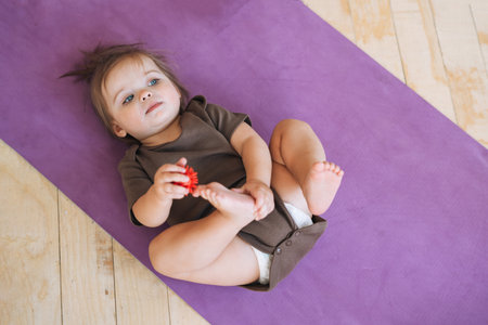 Cute baby girl with massage ball lying on fitness matの写真素材