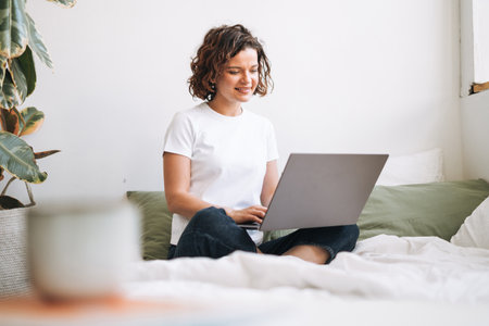 Young brunette woman in home clothes working on laptop from homeの写真素材