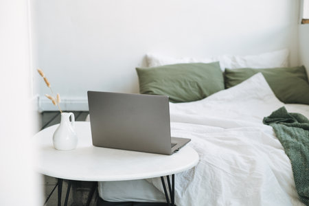 Opened laptop in scandinavian modern cozy bright interior in bedroom at homeの写真素材