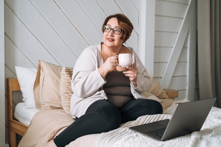 Smiling middle aged plus size woman working on laptop from homeの写真素材