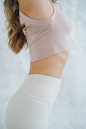 Crop close up photo of young woman in sportswear doing stretching on background of white wallの写真素材