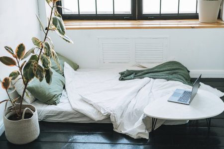 Opened laptop in scandinavian modern cozy bright interior in bedroom at homeの写真素材