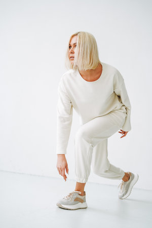 Full length portrait of smiling young blonde woman in sportswear on background of white wallの写真素材