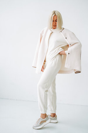 Full length portrait of smiling young blonde woman in sportswear on background of white wallの写真素材