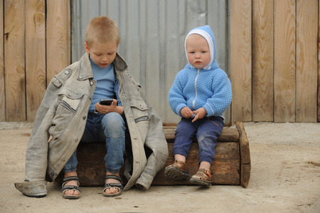 Two young guy plays with a phone and a prize for races on a rural farmstead in a hot summerの写真素材