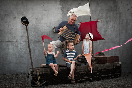 Three cute dude  with their daddy playing pirates on a wooden boat on a summer eveningの写真素材
