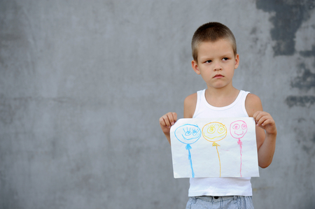 The senior boy in a large family is going to school and showing his drawings and a school backpackの写真素材