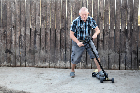 An elderly man tries to drive a scooter to teach his sons.の写真素材