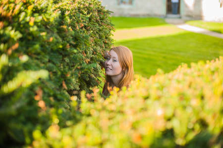 A girl looks out of bushes