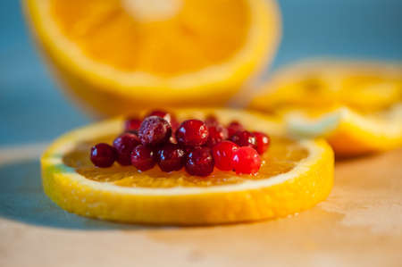 orange with cranberries on a wooden backgroundの写真素材