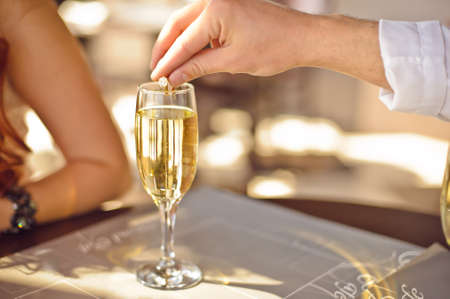 A man throws a wedding ring in a glass of champagne to ask his girlfriend to be his wifeの写真素材