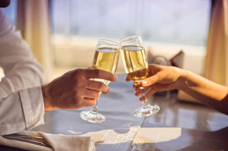 Hands Man and woman sitting at a table with glasses of champagneの写真素材