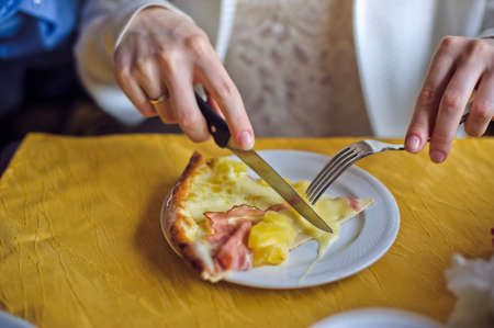 Woman cuts the pizza with cheese and ham, food conceptの写真素材