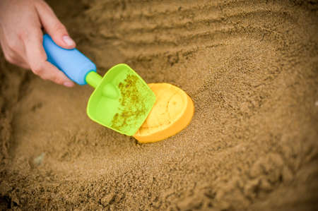 Hand making a sand mold using molds, tools for children to play in the sand