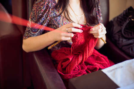 The woman knits a sweater red thread.の写真素材